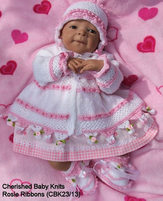 a baby doll laying on top of a pink blanket with hearts around her feet and head