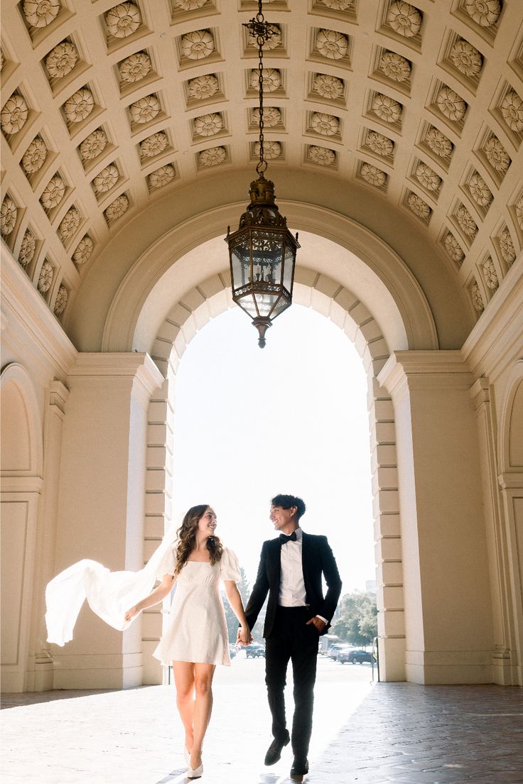 a bride and groom holding hands under an archway