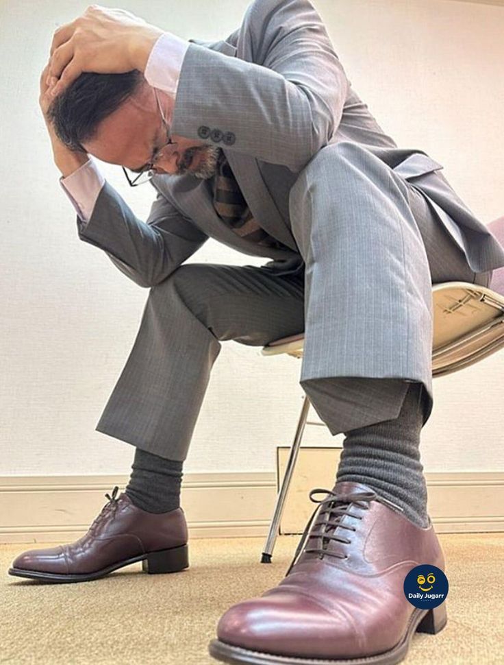 a man in a suit and tie sitting on a chair with his hands behind his head