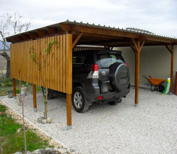 a car is parked in front of a carport with a wooden structure on top