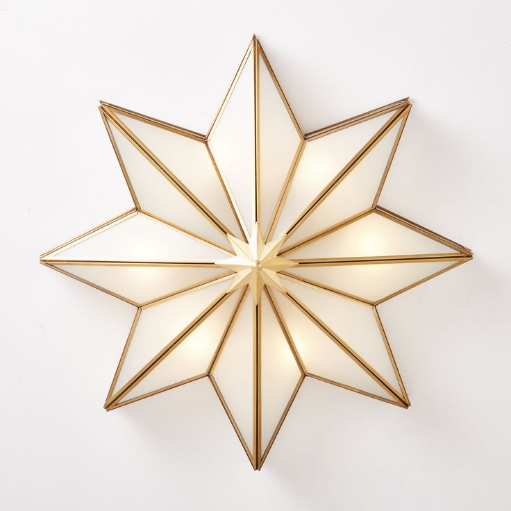 a gold star shaped light fixture on a white wall