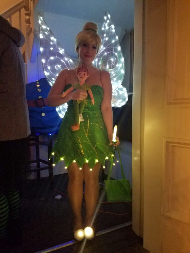 a woman dressed as tinkerbell holding a teddy bear