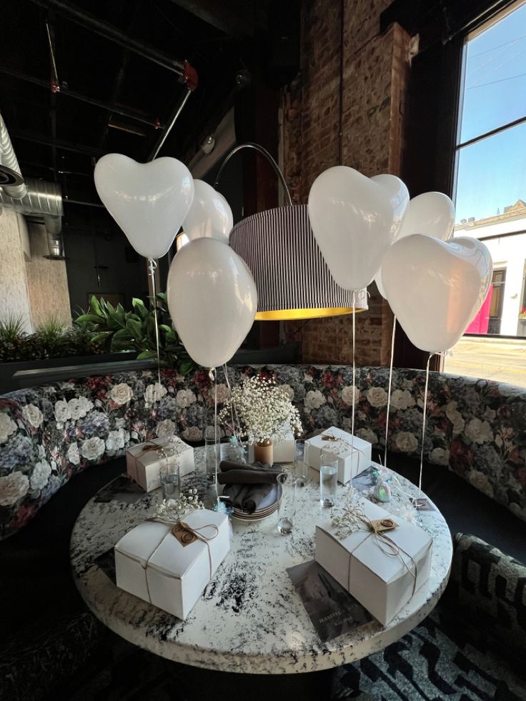 a table with white balloons and gifts on it