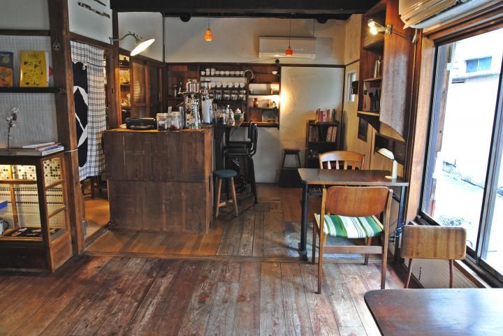 the inside of a small restaurant with wooden floors and tables in front of large windows