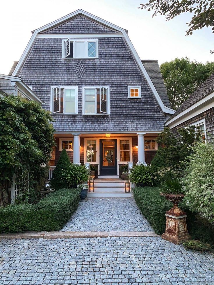 the front entrance to a large house with lots of bushes and shrubs on either side