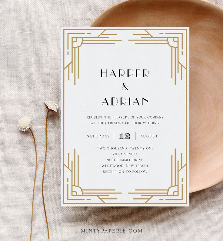 a white and gold wedding card sitting on top of a plate next to a flower