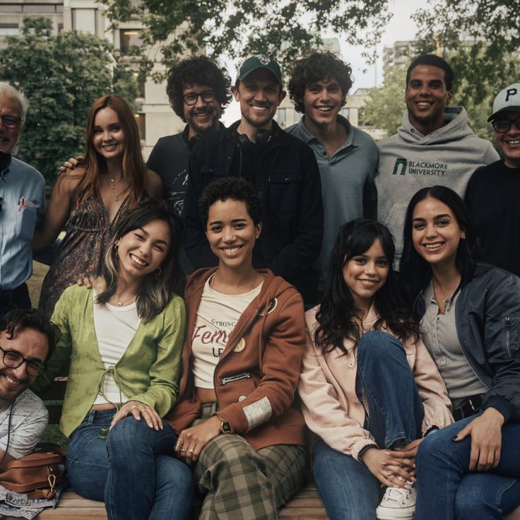 a group of young people sitting on top of a wooden bench next to each other