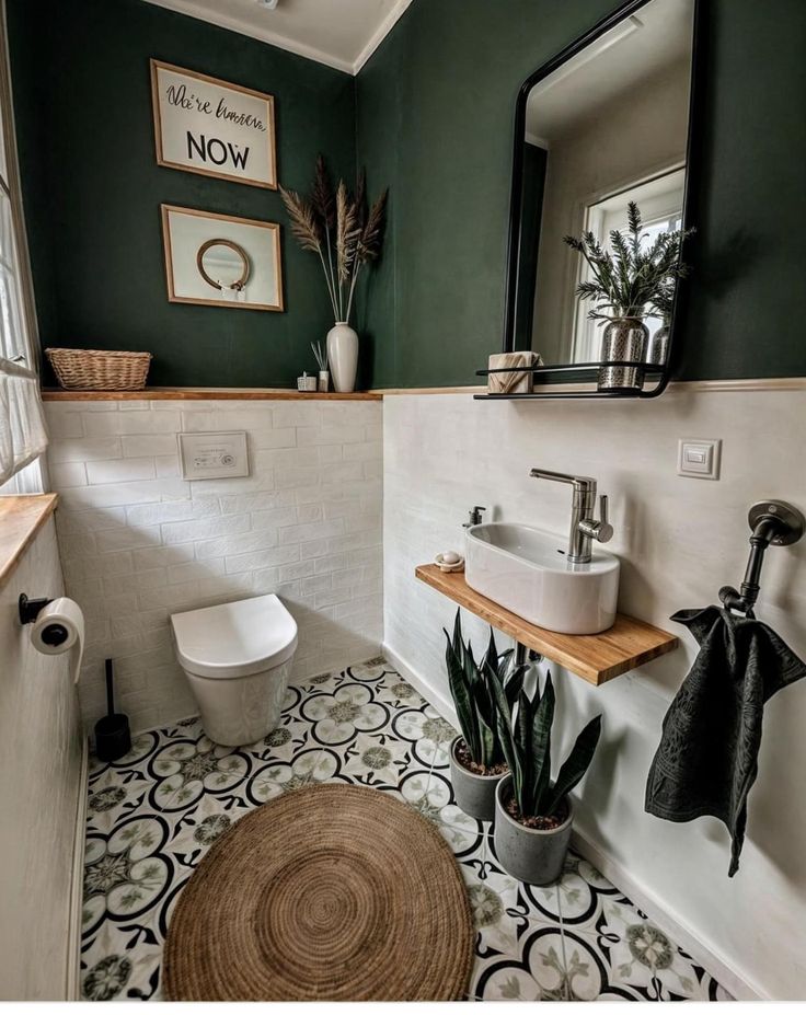 a bathroom with a toilet, sink and mirror on the wall next to a potted plant