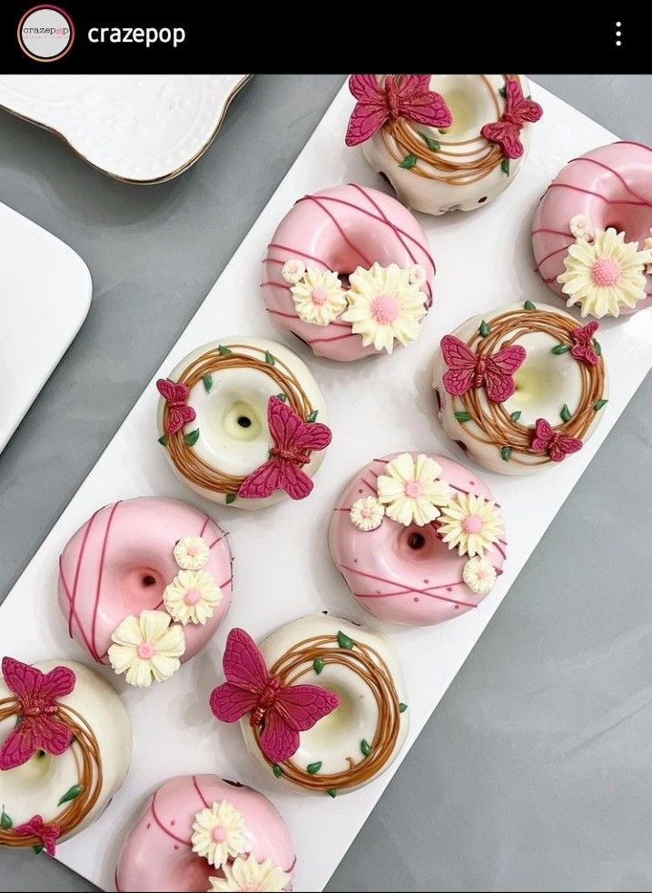 there are many donuts decorated with flowers on the plate and in the middle is a cupcake