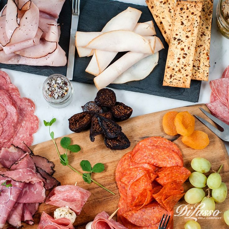 an assortment of meats and cheeses on a cutting board