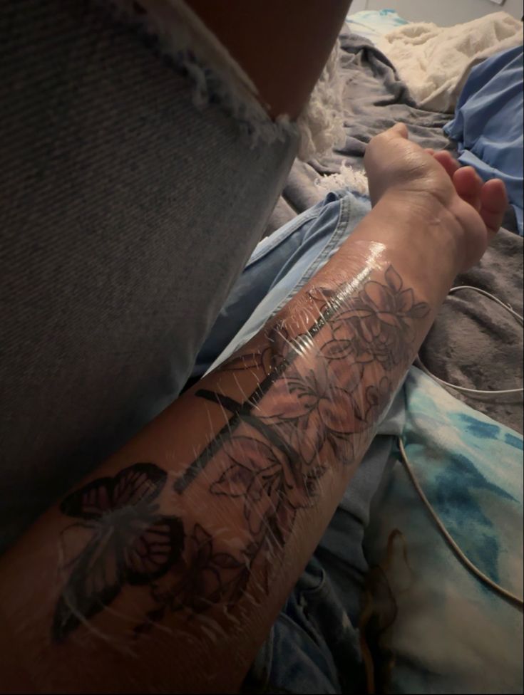 a person with a tattoo on their arm laying in bed next to a laptop computer