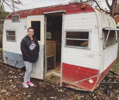 a woman standing in the doorway of an old trailer