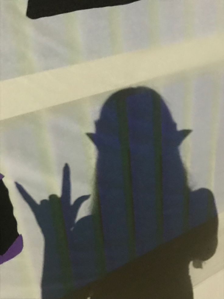 the shadow of a person sitting in a chair with his hand up to their face