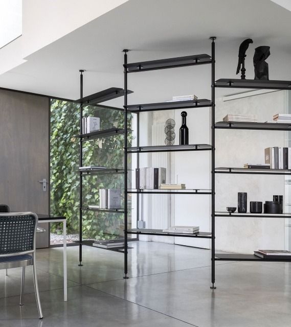 a room filled with lots of books and furniture next to a wall mounted book shelf