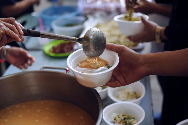 several people are serving themselves food from bowls