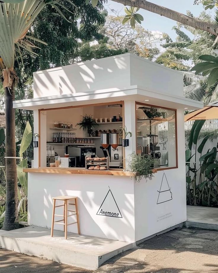 a small white building with plants on the outside and an awning over it that says lemonade