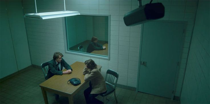 two people sitting at a table in a dark room, one is on the phone