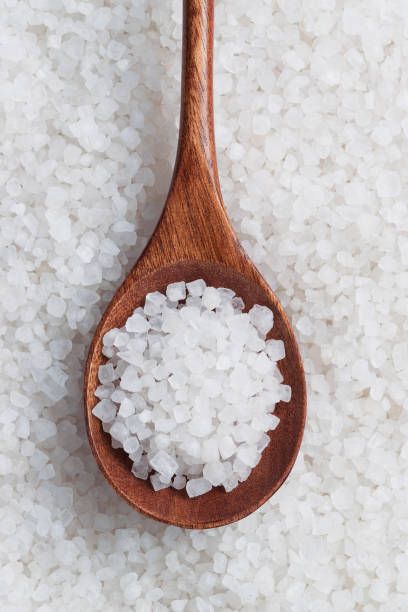 a wooden spoon filled with sea salt on top of white rice