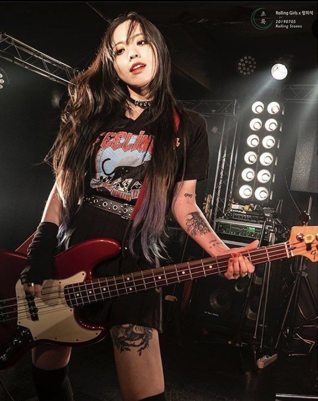 a woman with long hair holding a bass guitar in front of some stage lights and sound equipment