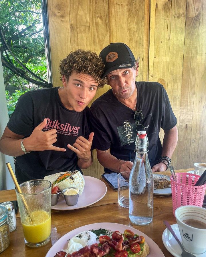 two men sitting at a table with food and drinks