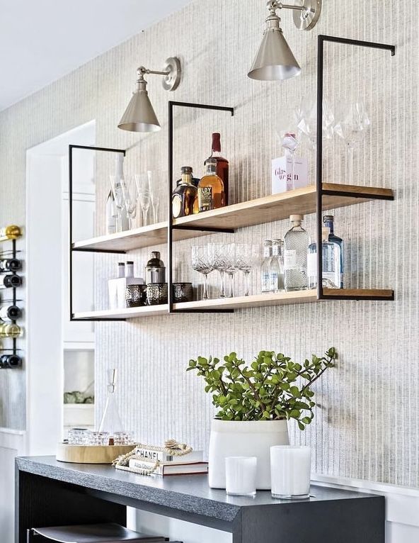 a shelf with bottles and glasses on it next to a potted plant in a vase