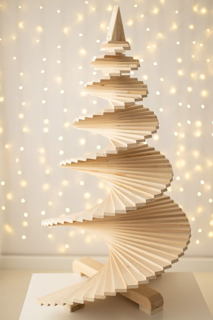 a wooden christmas tree made out of folded paper and string lights are in the background