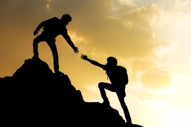 two people reaching out to each other on top of a mountain with the sun in the background