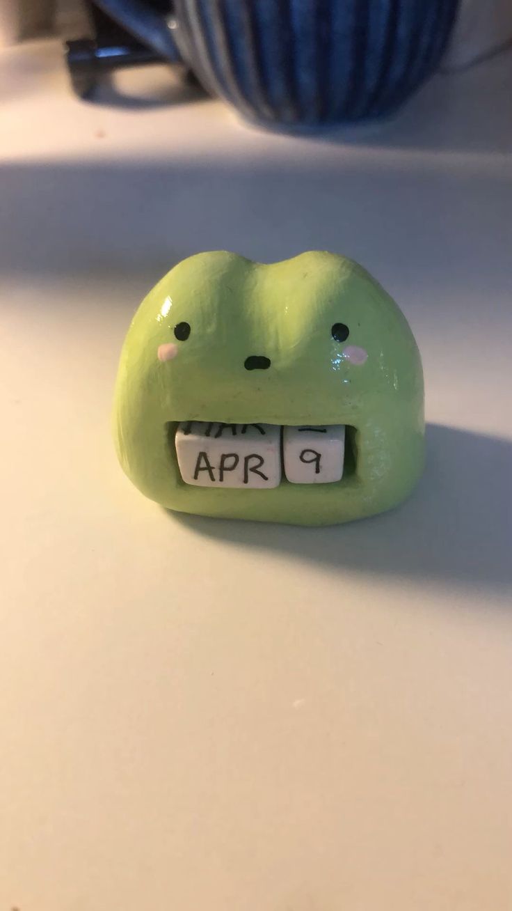 a green frog shaped alarm clock sitting on top of a counter