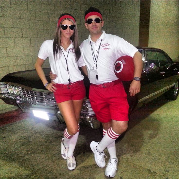 a man and woman in red shorts standing next to a car