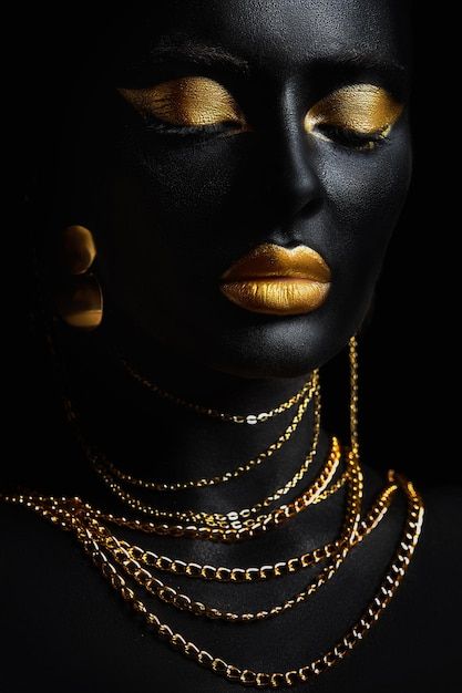 a woman with gold makeup and jewelry on her face, wearing black skin and gold necklaces