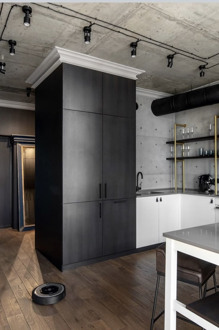 a kitchen with black and white cabinets, wooden floors and an industrial style ceiling fan