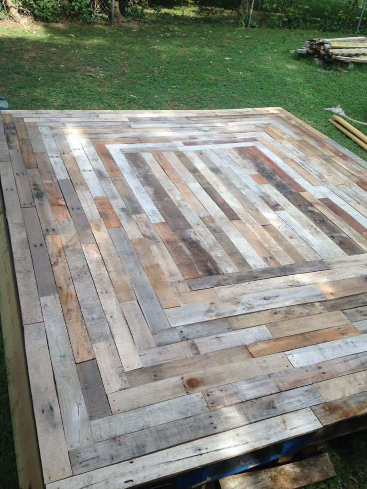 a large wooden floor sitting on top of a lush green field