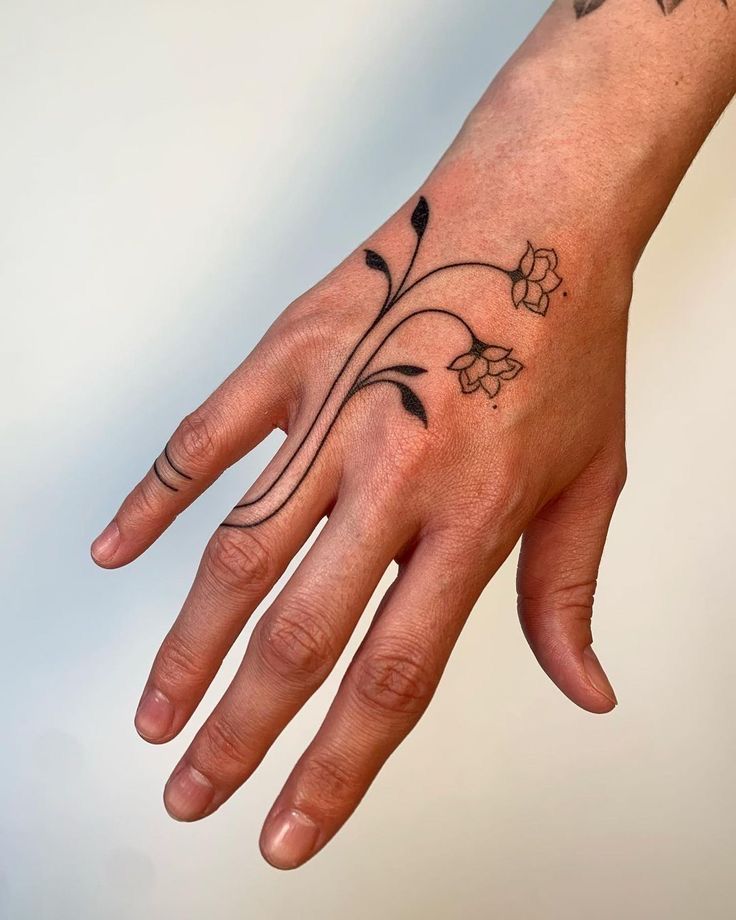 a person's hand with a flower tattoo on it