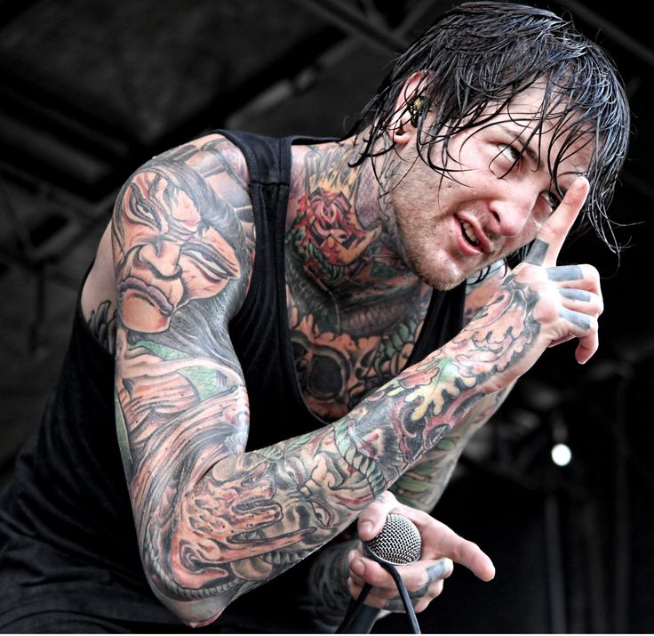 a man with tattoos on his arm holding a microphone