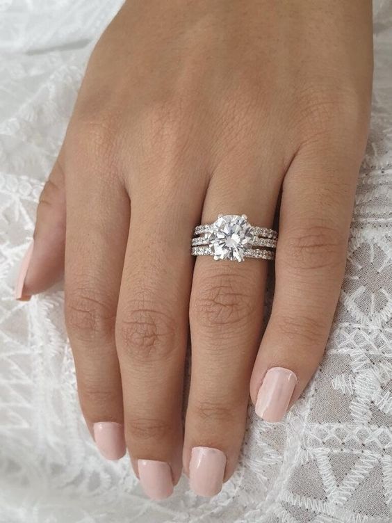 a woman's hand with two engagement rings on it