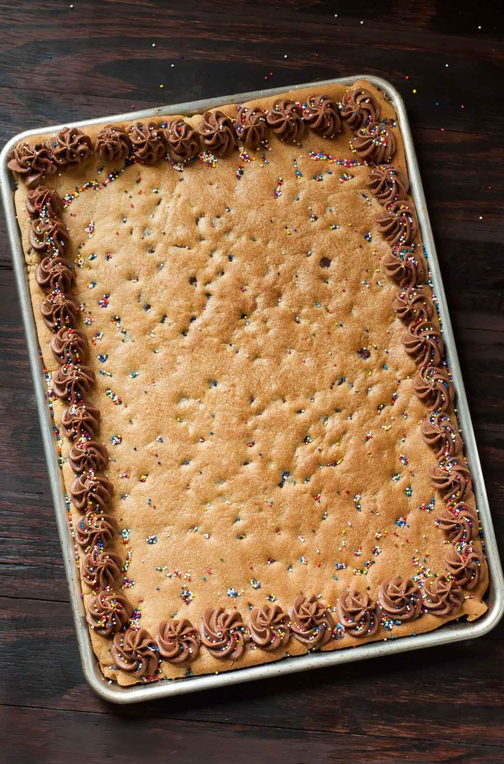 a square cake with chocolate frosting and sprinkles on it in a pan