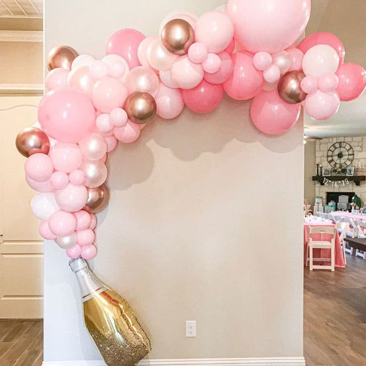 the balloon arch is decorated with pink, gold and white balloons