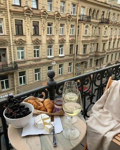 a glass of wine and some food on a table with a view of the city