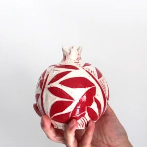 a hand holding a red and white ornament