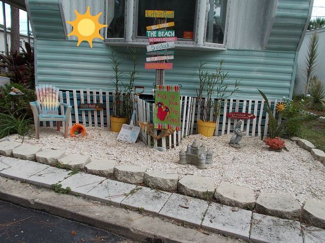 a mobile home is decorated with colorful signs and flowers on the front lawn, along with other decorations