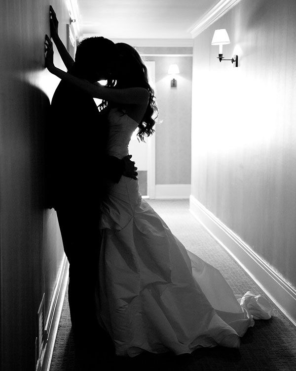 a bride and groom are kissing in the hallway at their wedding reception, black and white photograph