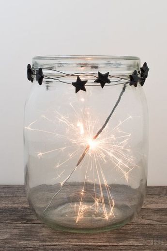 a glass jar filled with fireworks on top of a wooden table