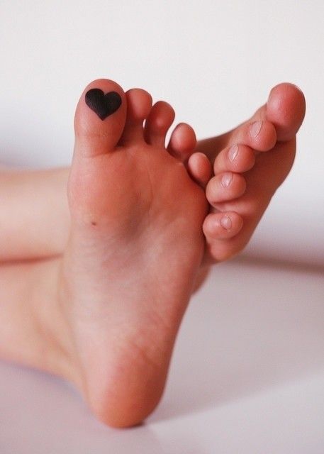 a close up of a person's bare feet with a heart on their toe