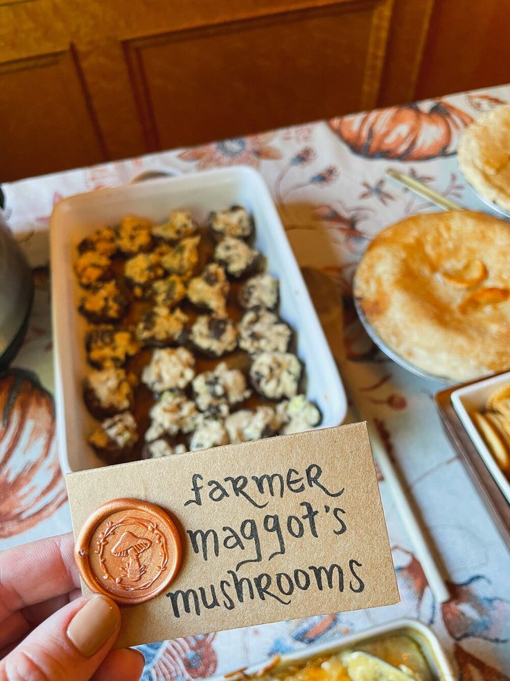 a person holding up a sign that says farmer maggo's mushrooms and other food