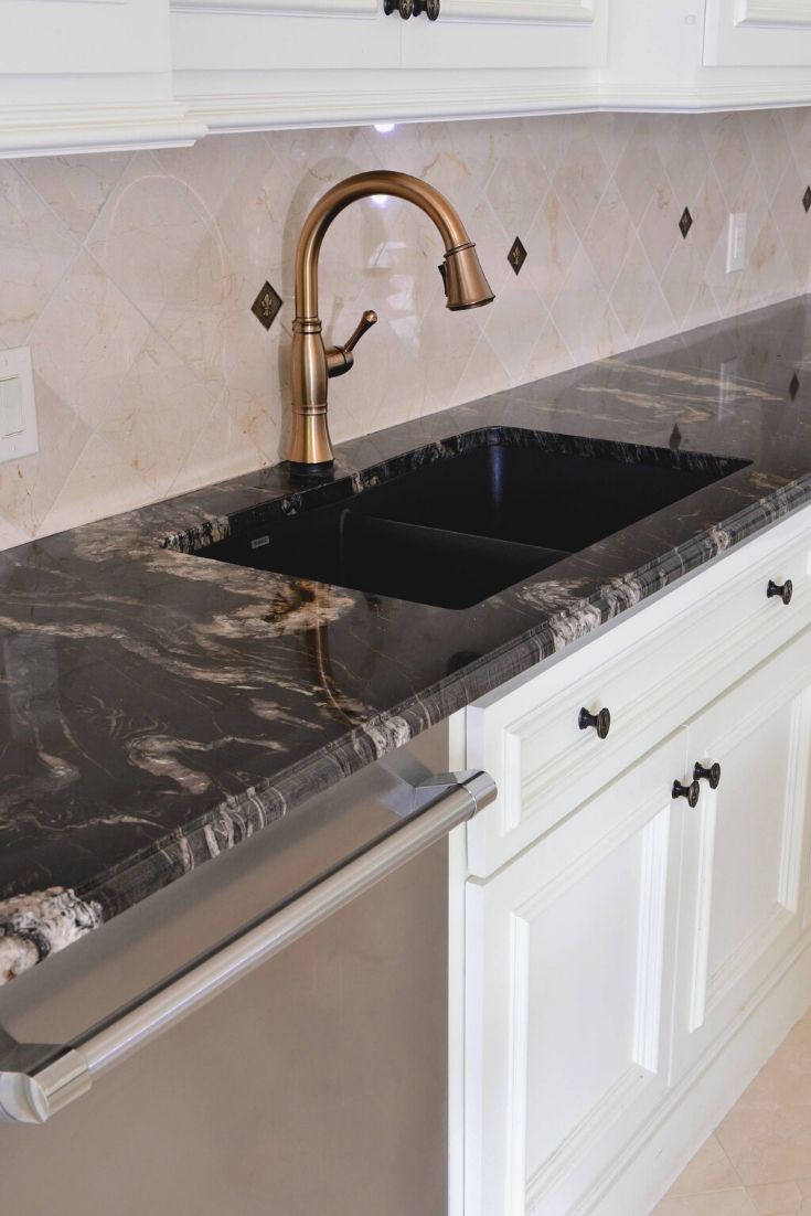 a kitchen with marble counter tops and stainless steel dishwasher in the center, along with white cabinets