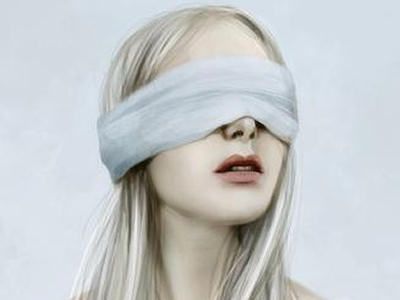 a woman with her eyes closed and blind folded over her face, in front of a white background