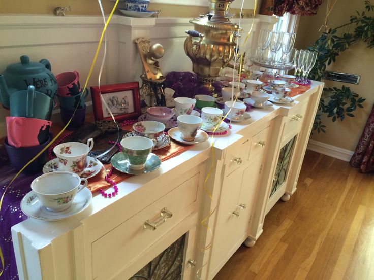 there are many cups and bowls lined up on the buffet table with balloons in the air