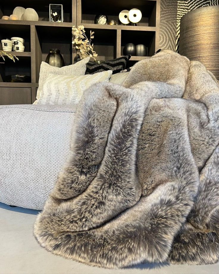 a fur rug is laying on the floor in front of a bookcase and couch