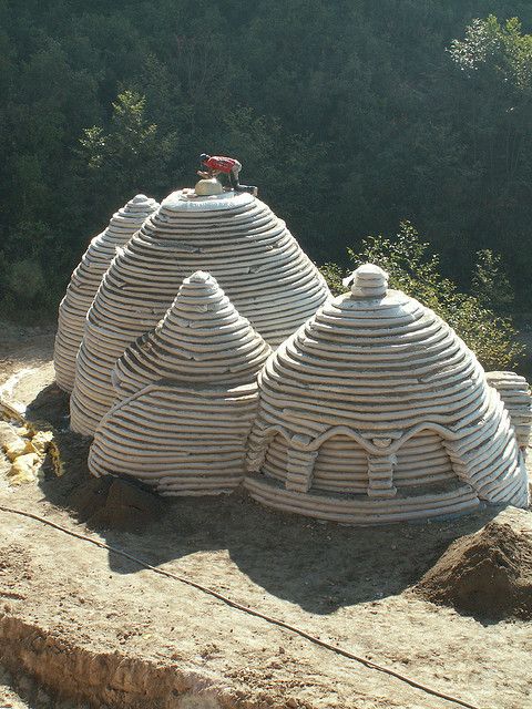 a large building made out of sand sitting on top of a dirt hill next to trees