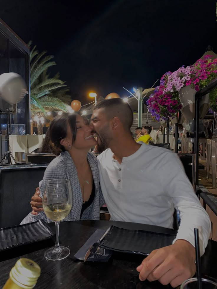 a man and woman sitting at a table kissing